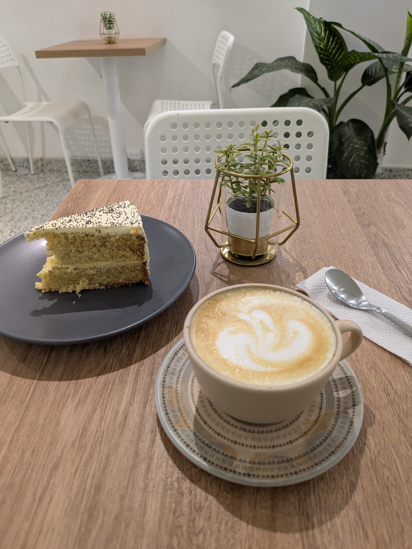 Porción de torta de amapola servida junto a un latte